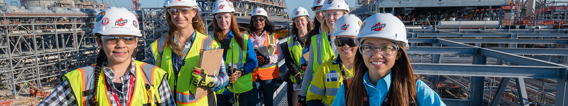 A group of women in protective equipment standing in line with construction site in background
